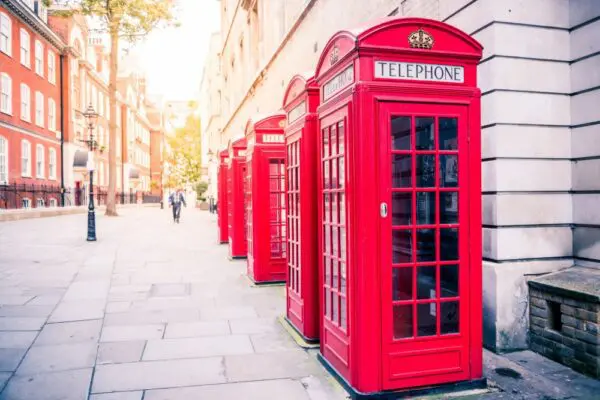 Row of classic red telephone boxes lining a London street