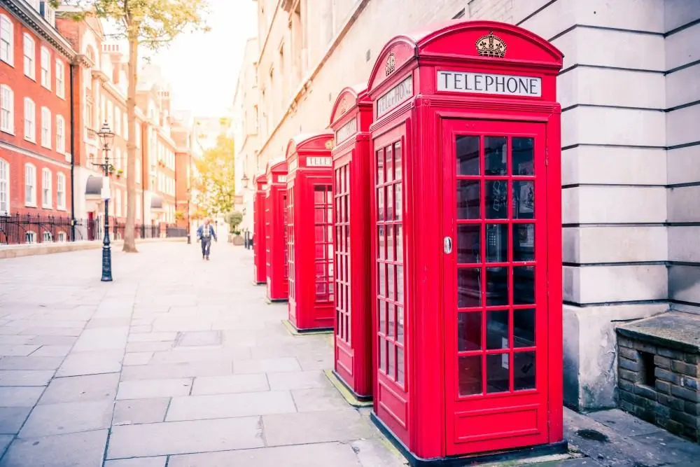 Row of classic red telephone boxes lining a London street