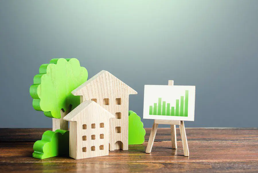 Wooden house models and trees beside an easel showing UK rental market growth chart - future of UK rental market trends