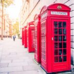 Row of classic red telephone boxes lining a London street