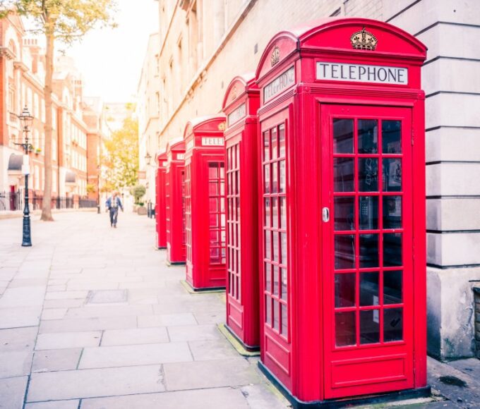 Row of classic red telephone boxes lining a London street